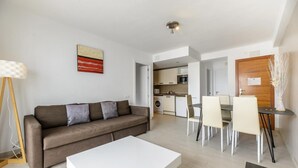 A modern living room with a sofa, a coffee table, and a dining area with chairs and a table. - Esmeralda apartment in Ibiza!!! 201 (Ibiza / Eivissa)