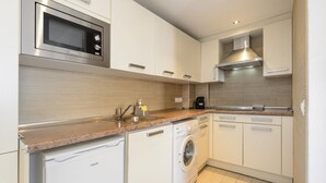 A compact kitchen with a microwave, washing machine, and a built-in oven. - Esmeralda apartment in Ibiza!!! 202 (Ibiza / Eivissa)