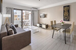 A modern living room with a sofa, coffee table, TV, dining table, and chairs. - Esmeralda apartment in Ibiza!!! 202 (Ibiza / Eivissa)