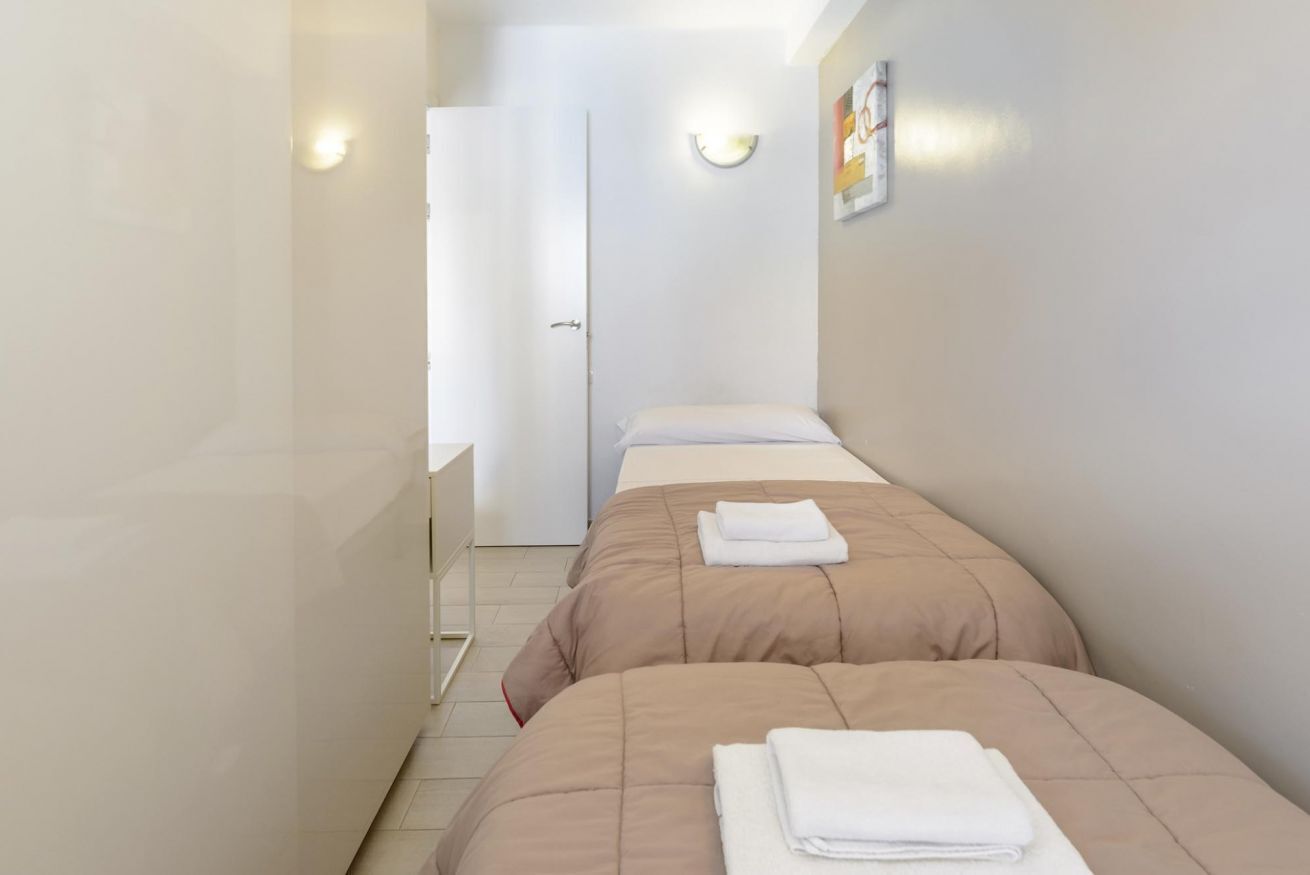 A hotel room with two beds, a bathroom, and a door leading to another room.