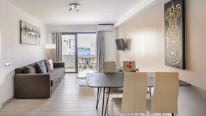 A modern living room with a sofa, dining table, chairs, a TV, and artwork. - Esmeralda apartment in Ibiza!!! 202 (Ibiza / Eivissa)