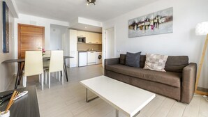 A modern living room with a sofa, a coffee table, and a dining area with chairs. - Esmeralda apartment in Ibiza!!! 202 (Ibiza / Eivissa)