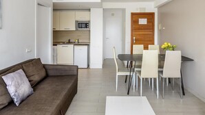 A modern living room with a sofa, a dining table with chairs, and a kitchen in the background. - Esmeralda apartment in Ibiza!!! 301 (Ibiza / Eivissa)