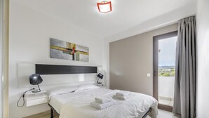 A hotel room with a bed, bedside tables, a nightstand, a wall-mounted artwork, and a view through a door. - Esmeralda apartment in Ibiza!!! 301 (Ibiza / Eivissa)