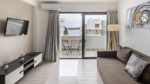 A modern living room with a flat-screen TV, a sofa, a coffee table, and a balcony with a view of the sea. - Esmeralda apartment in Ibiza!!! 301 (Ibiza / Eivissa)