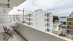A balcony with a table and chairs, overlooking a residential area with multiple buildings and a clear view of the sea. - Esmeralda apartment in Ibiza!!! 301 (Ibiza / Eivissa)