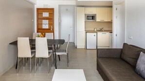 Un salon moderne comprenant un coin repas, une kitchenette et une porte dotée d’un tableau d’affichage.