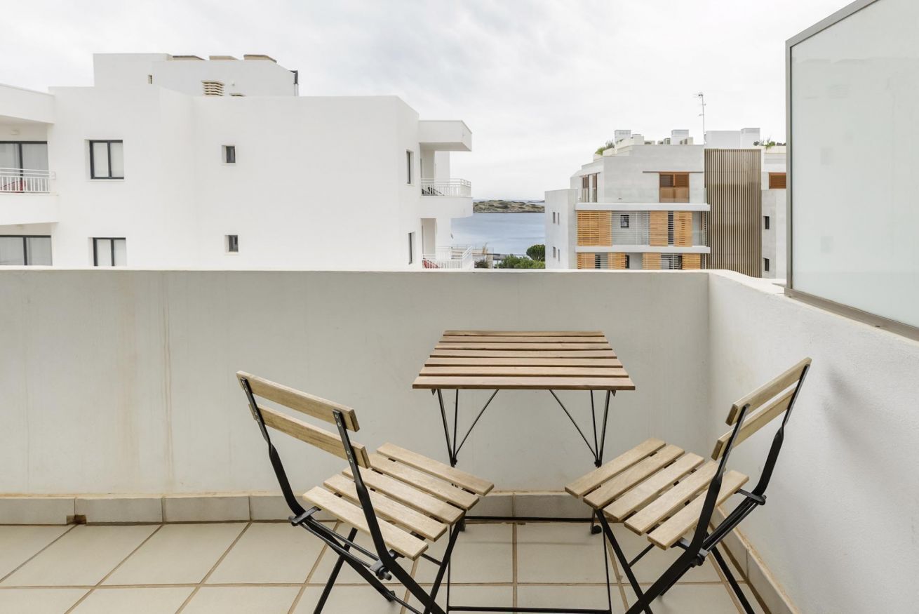 Ein Balkon mit Tisch und Stühlen mit Blick auf eine Stadtlandschaft mit Gebäuden und einem Gewässer.