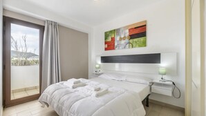 Une chambre d’hôtel avec un lit, une table de chevet, une œuvre d’art accrochée au mur, une fenêtre avec des rideaux et une vue sur l’extérieur.