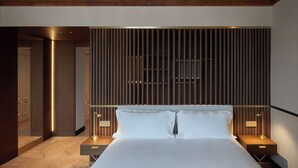 A modern hotel room with a large bed, wooden headboard, and two bedside tables with lamps. - Amabilia Suites (Milan)