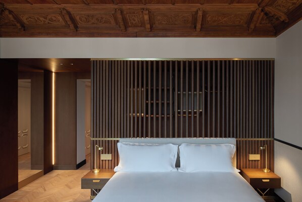 A modern hotel room with a large bed, wooden headboard, and two bedside tables with lamps. - Amabilia Suites (Milan)