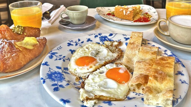 A breakfast setting with croissants, eggs, and orange juice on a table. - Amabilia Suites (Milan)