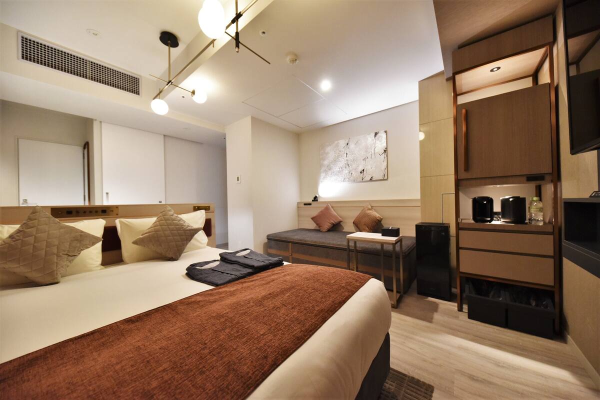 Een moderne hotelkamer met een groot bed, een bureau, een koffieapparaat en een televisie.