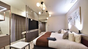 A modern hotel room with a large bed, bedside tables, a desk, and a seating area.