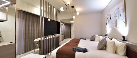Quarto de hotel moderno com uma cama grande, mesas de cabeceira, uma escrivaninha e um espaço de estar.