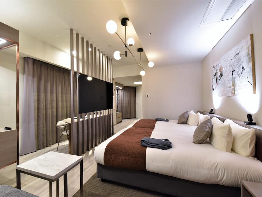 Una habitación de hotel moderna con una cama grande, mesitas de noche, un escritorio y una zona de estar.
