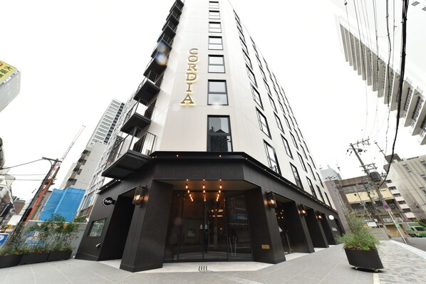 Une entrée d’hôtel moderne, avec une enseigne bien visible, de grandes fenêtres et un auvent noir.
