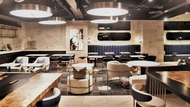 A modern restaurant with round tables, cushioned seating, and pendant lighting.