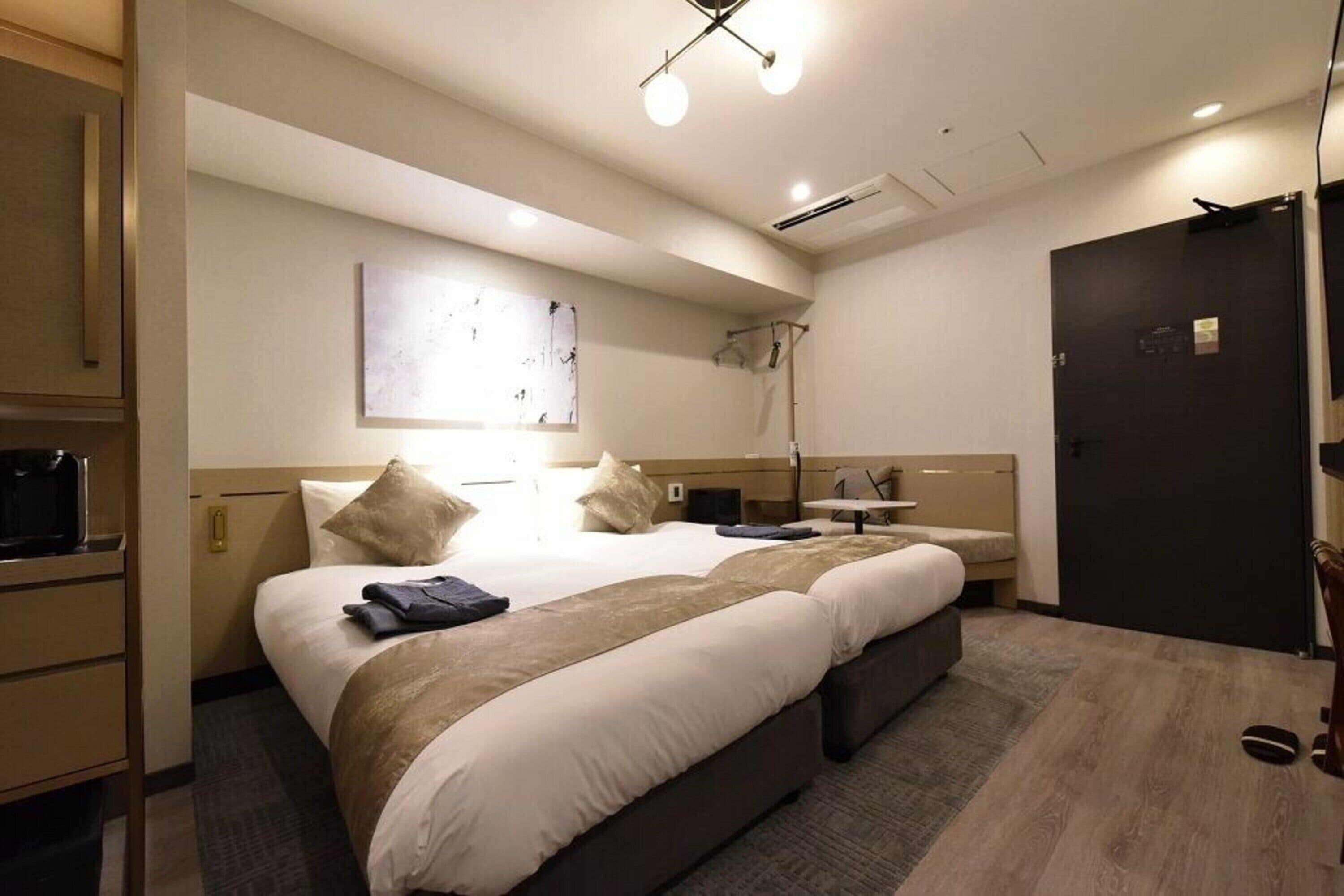 Ein Hotelzimmer mit einem großen Bett, Nachttischen, einem Schreibtisch und einem Kleiderschrank.