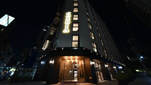 A modern hotel with a prominent 'CORDIA' sign, large windows, and a well-lit entrance.