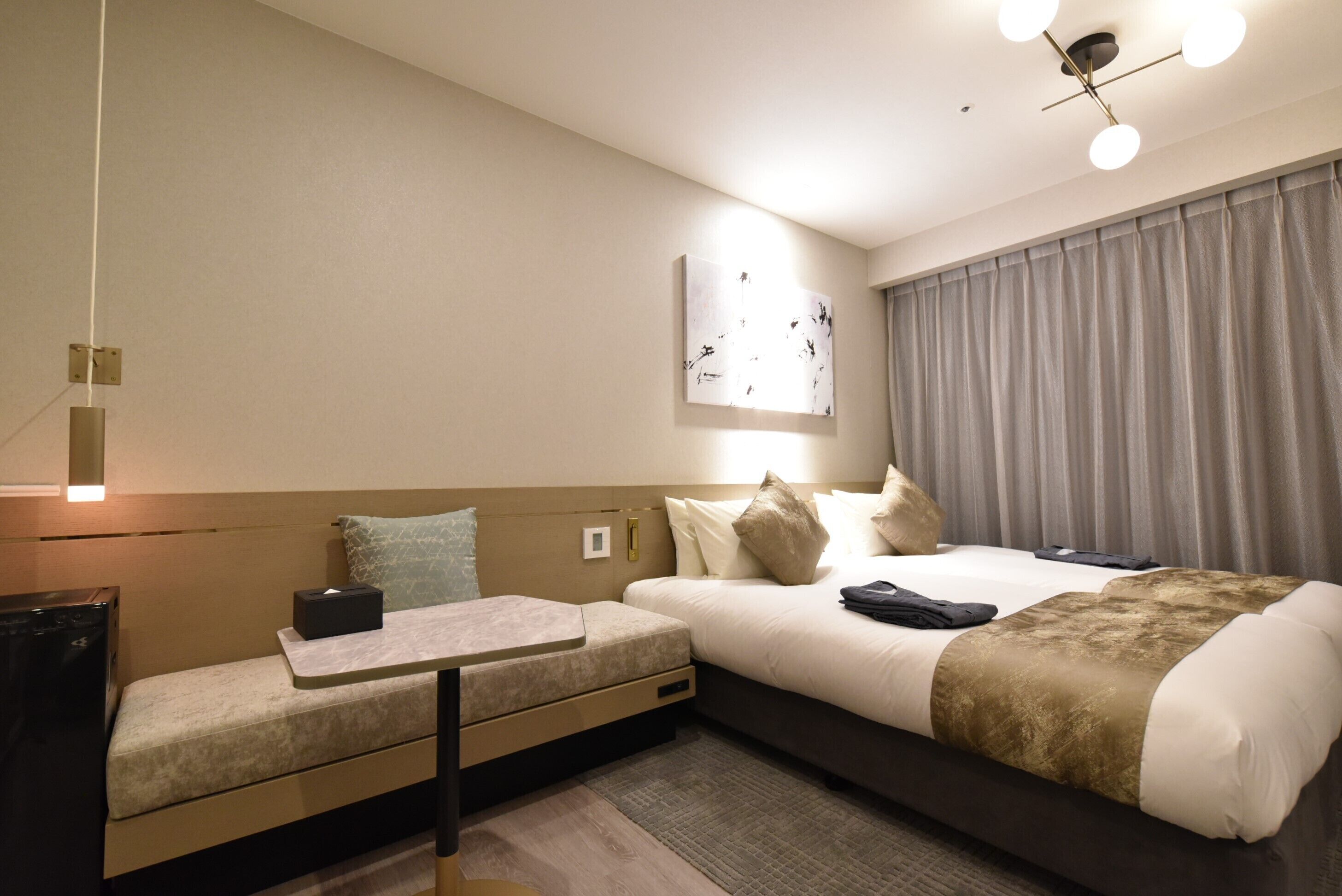 Una habitación de hotel moderna con una cama, un escritorio pequeño y una zona de estar.