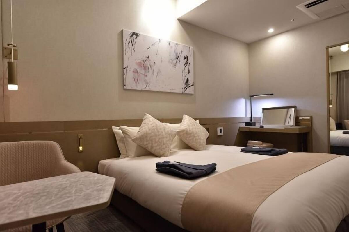 Een hotelkamer met een bed, een bureau, een stoel, een schilderij aan de muur en een nachtkastje met een lamp.