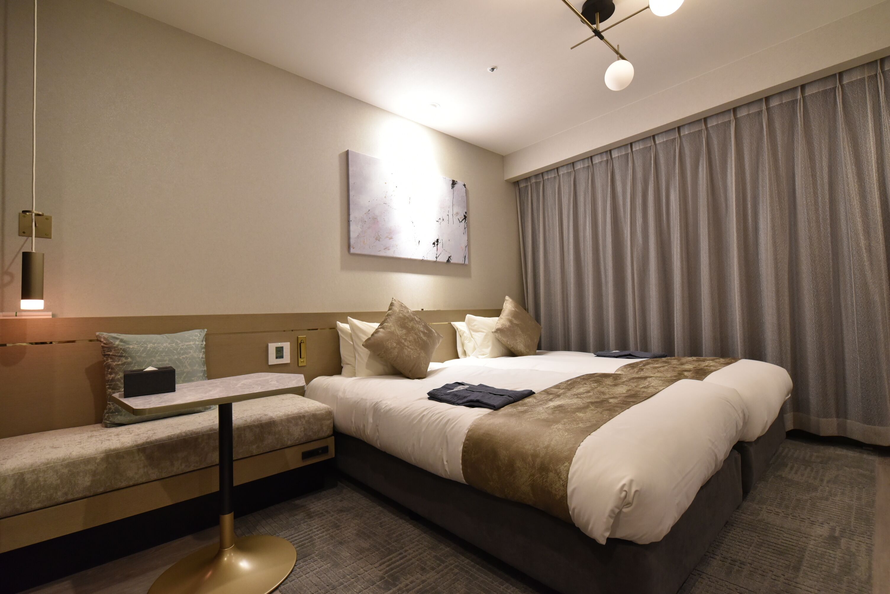 Ett modernt hotellrum med en stor säng, en soffa, ett sängbord och ett konstverk som hänger på väggen.