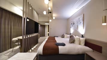 Una habitación de hotel moderna con una cama grande, un televisor de pantalla plana, un escritorio y una zona de estar.