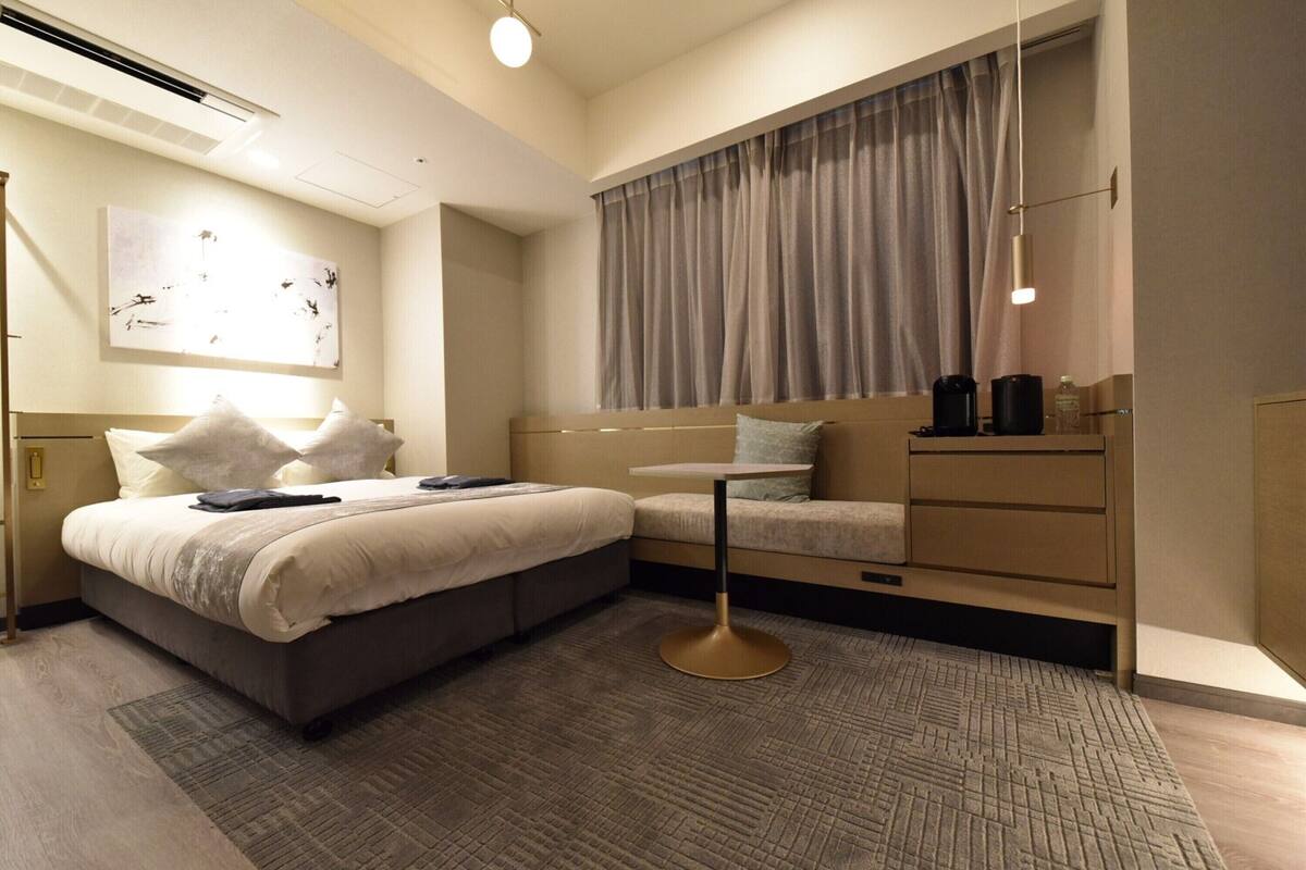 Een moderne hotelkamer met een bed, nachtkastje en bureau.
