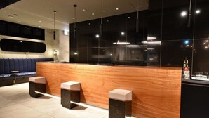A modern reception area with a wooden counter, black cabinets, and marble stools.