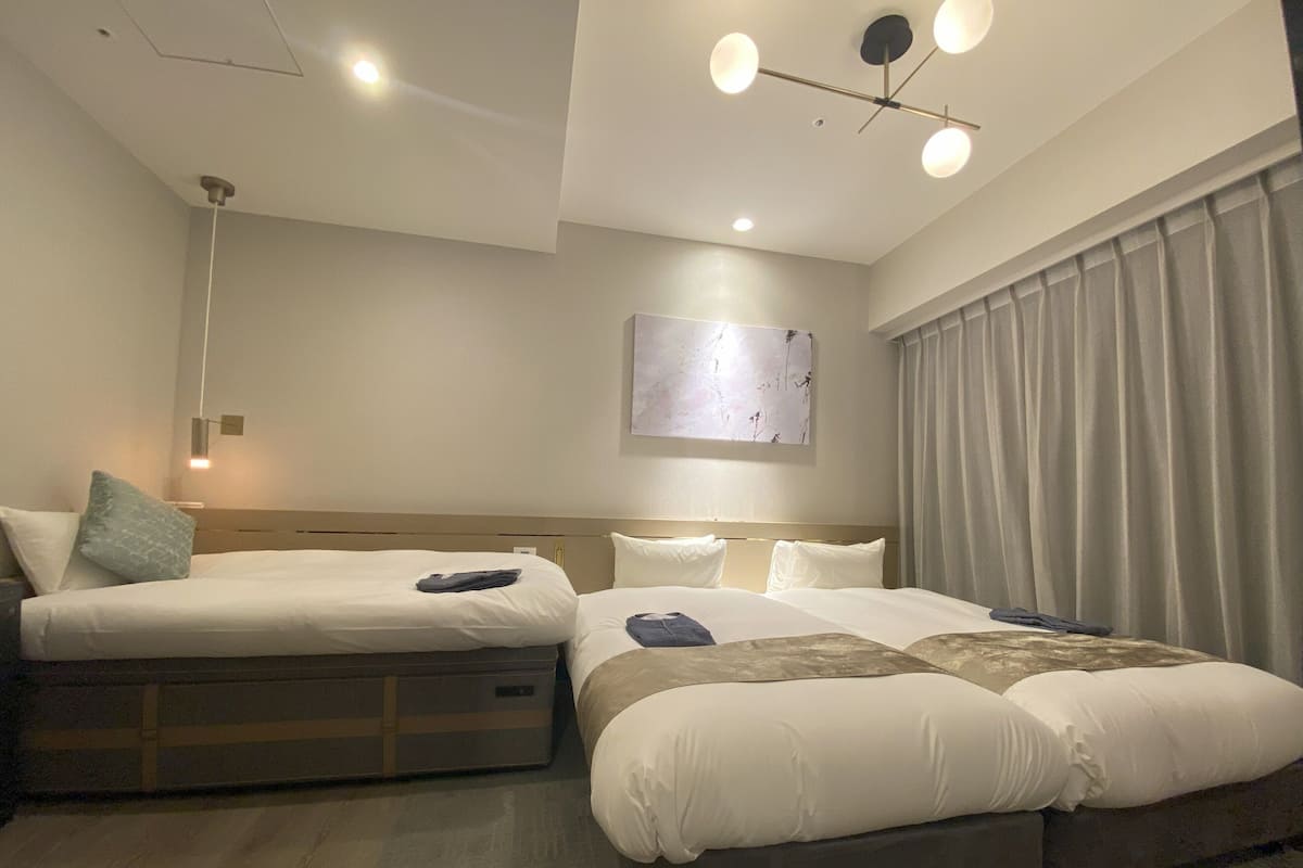 Hotelkamer met twee bedden, een plafondlamp, een kunstwerk aan de muur en een raam met gordijnen.