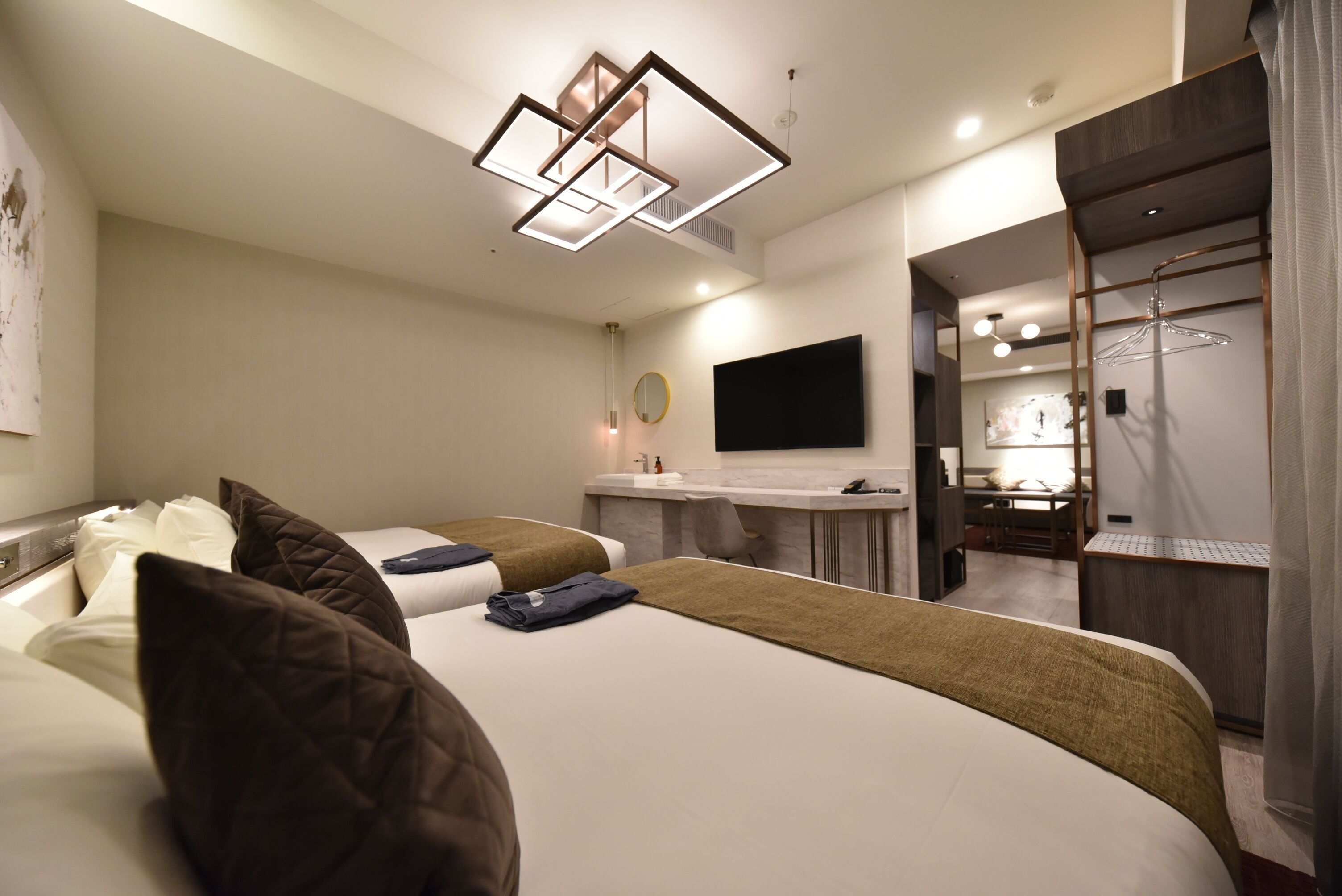 A modern hotel room with a large bed, a desk, a mirror, and a TV.