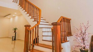 A spacious interior with a wooden staircase, a green rug, and a potted plant. - Jolie House II - Villa 2 Double Rooms - Charming (Thành phố Đà Lạt)
