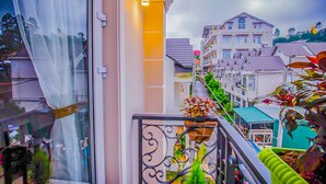 A balcony with a metal railing, a potted plant, and a view of residential buildings. - Jolie House II - Villa 2 Double Rooms - Charming (Thành phố Đà Lạt)
