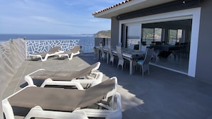 Une terrasse sur le toit, dotée de chaises longues, d’un espace repas et offrant une vue sur la mer.