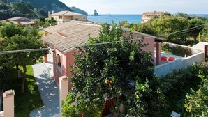 Zona residencial con vista al mar, una imponente formación rocosa y un edificio con techo de tejas.