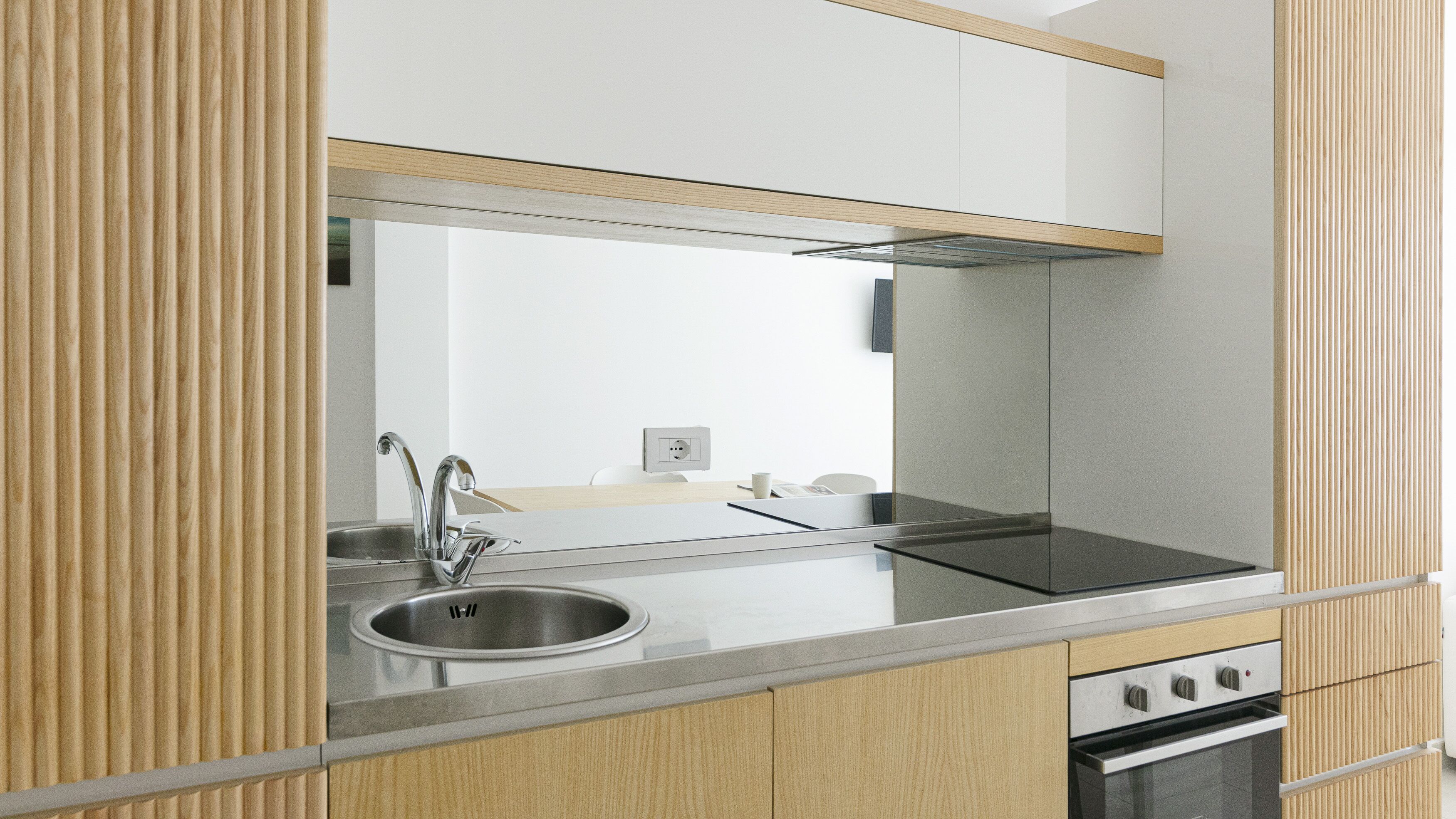 A modern kitchen with a stainless steel sink, a built-in oven, and wooden cabinetry.