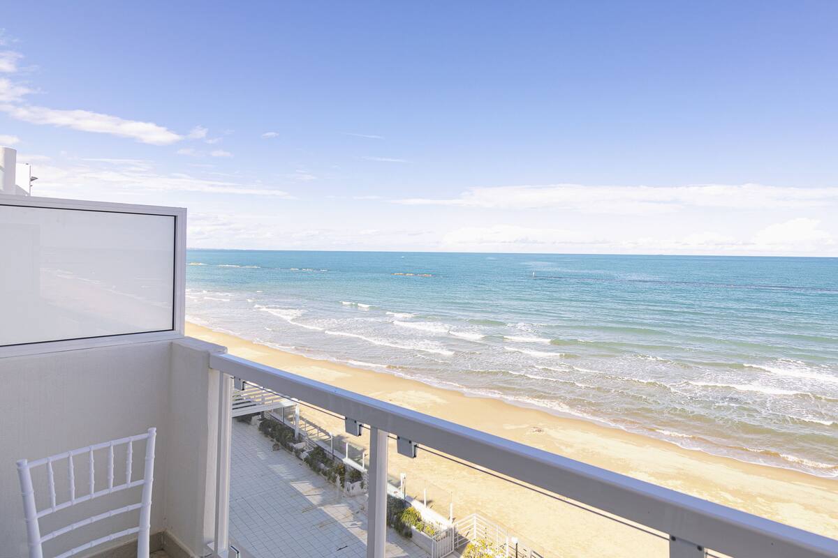 A balcony with a view of the beach and ocean.