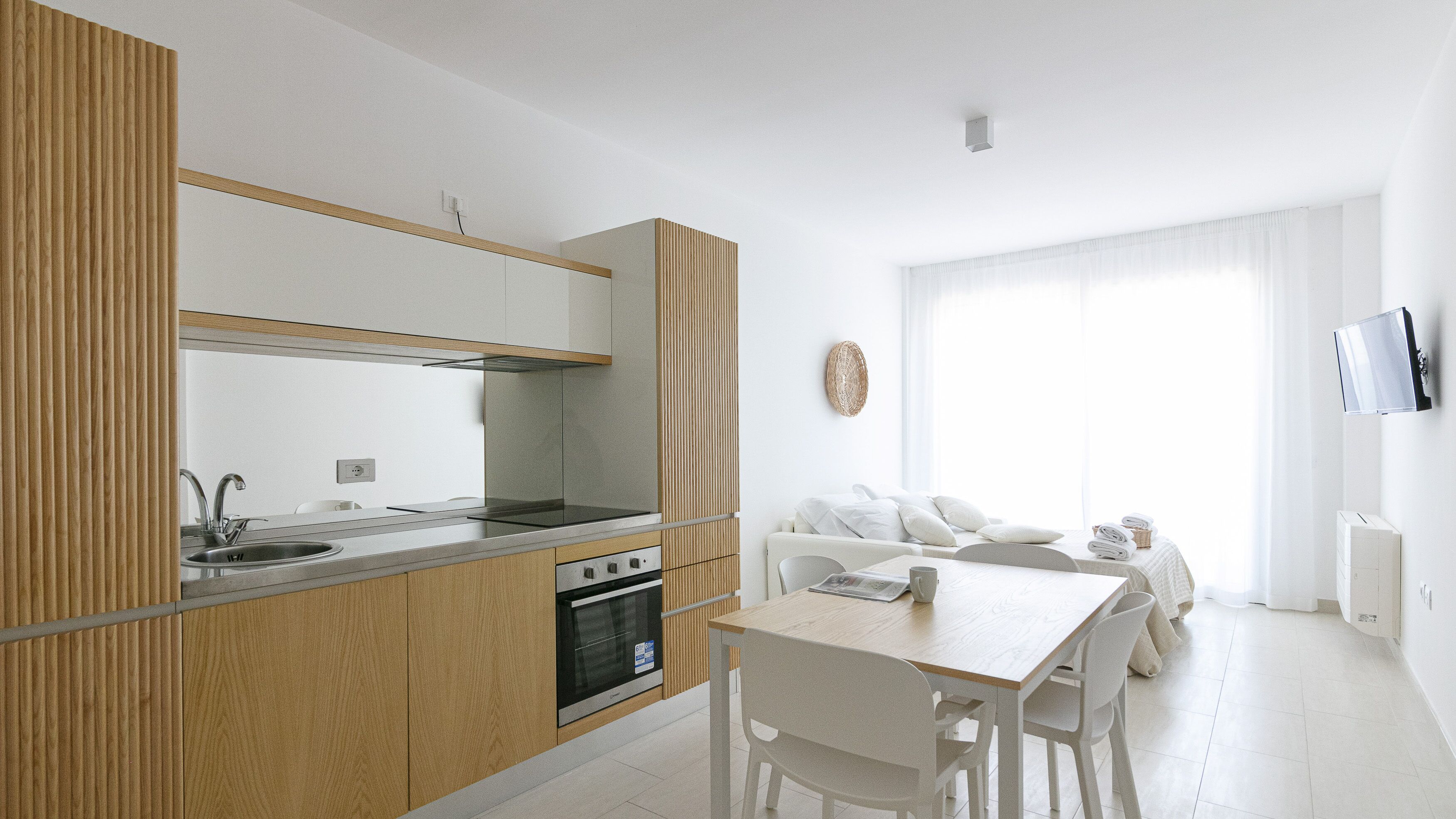 Una cocina moderna con horno integrado, un fregadero y una zona de comedor con mesa y sillas.