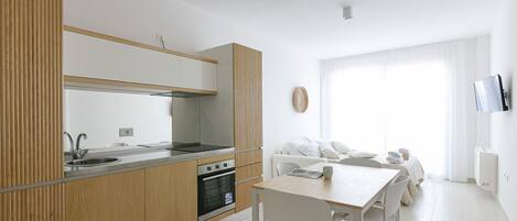 Una cocina moderna con horno integrado, un fregadero y una zona de comedor con mesa y sillas.