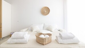 Une chambre bien rangée, avec un lit, des oreillers et un panier rempli de serviettes.