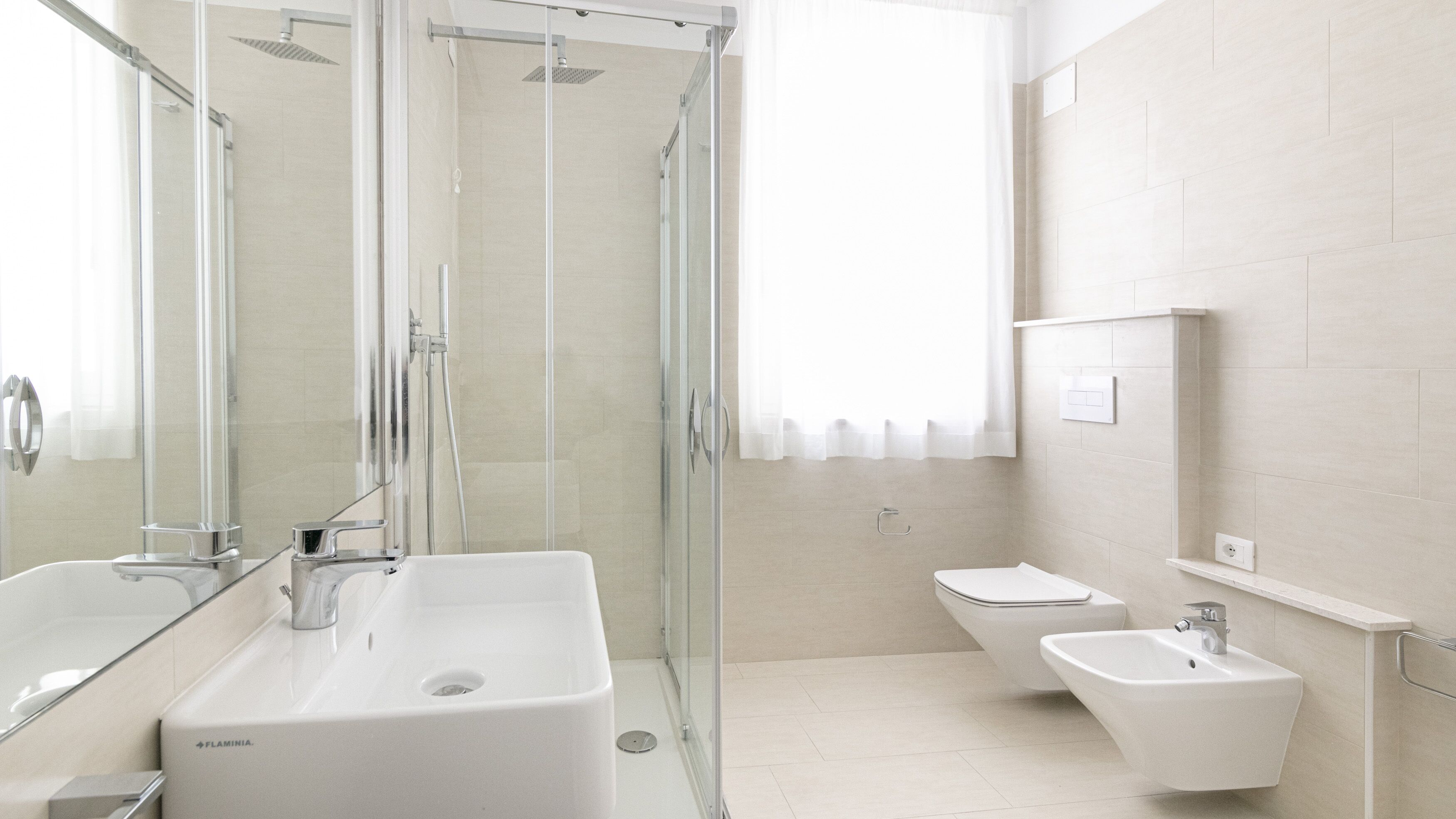A modern bathroom with a glass-enclosed shower, a large sink, and a bidet.