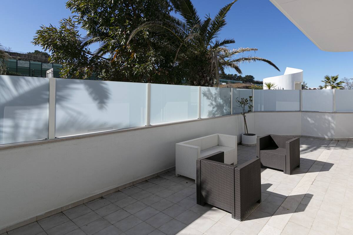 A rooftop patio with two wicker sofas, a small table, and a potted plant.
