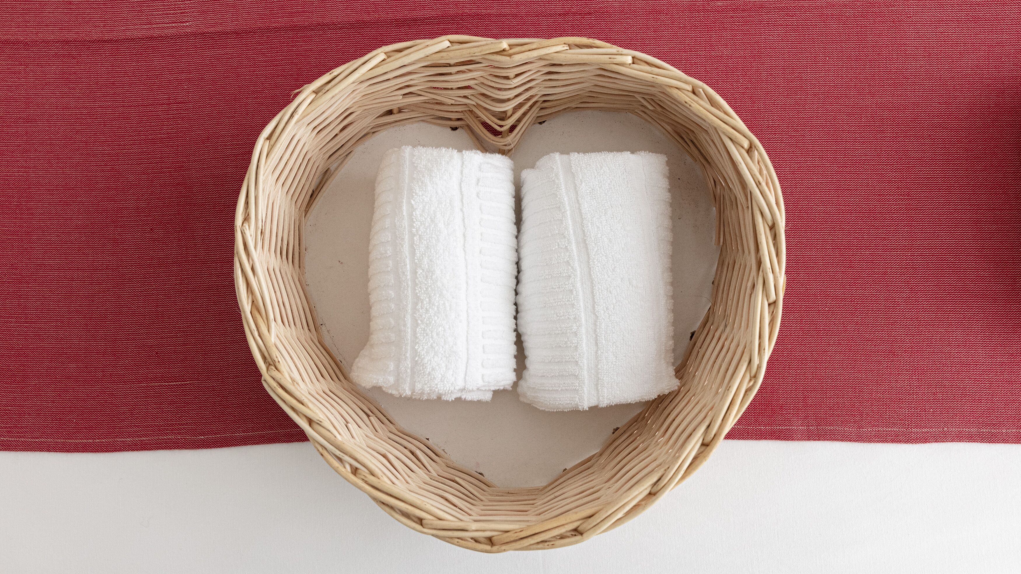 A wicker basket with two white towels placed inside it.