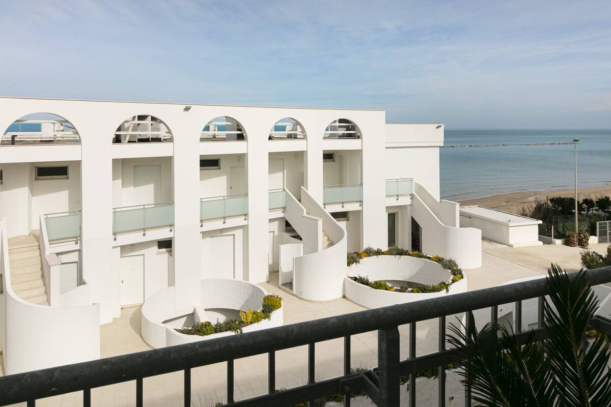 A modern building with multiple balconies and a view of the sea.