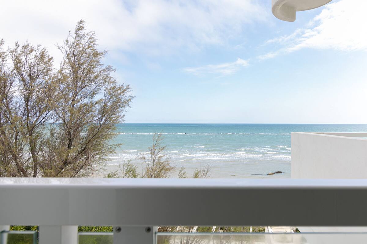A balcony with a view of the ocean and beach.