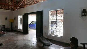 Une pièce avec un plafond haut, un banc, une statue et une voiture visible à travers une porte ouverte.
