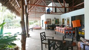 Un vaste espace de détente extérieur doté d’un toit de chaume, de sièges confortables et d’un bar.