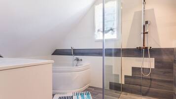 Une salle de bain moderne avec une baignoire sur pieds, une douche à parois de verre et une fenêtre laissant entrer la lumière naturelle.