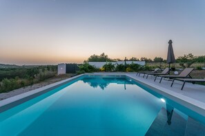 A rectangular swimming pool with clear blue water, surrounded by a low white wall. There are lounge chairs and a covered umbrella on the right side. - Modern villa BlackWood in Crno, secluded area, near Zadar center, near the beach, private pool, en suite bathrooms (Crno)